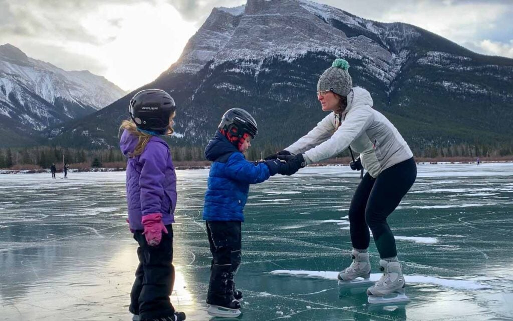 Celine Brewer, owner of TravelBanffCanada.com, helping her son learn to ice skate on Gap Lake near Canmore.