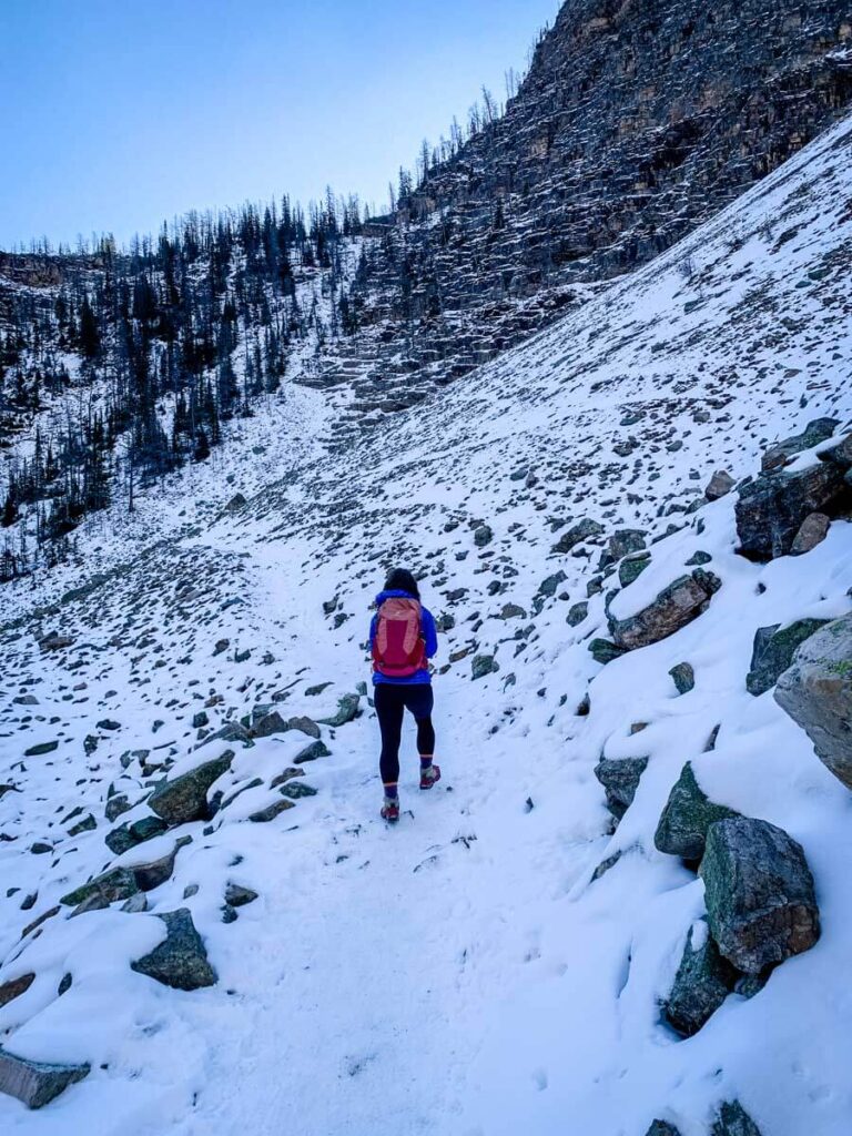 A woman hikes on the snow Banff Big Beehive trail in October