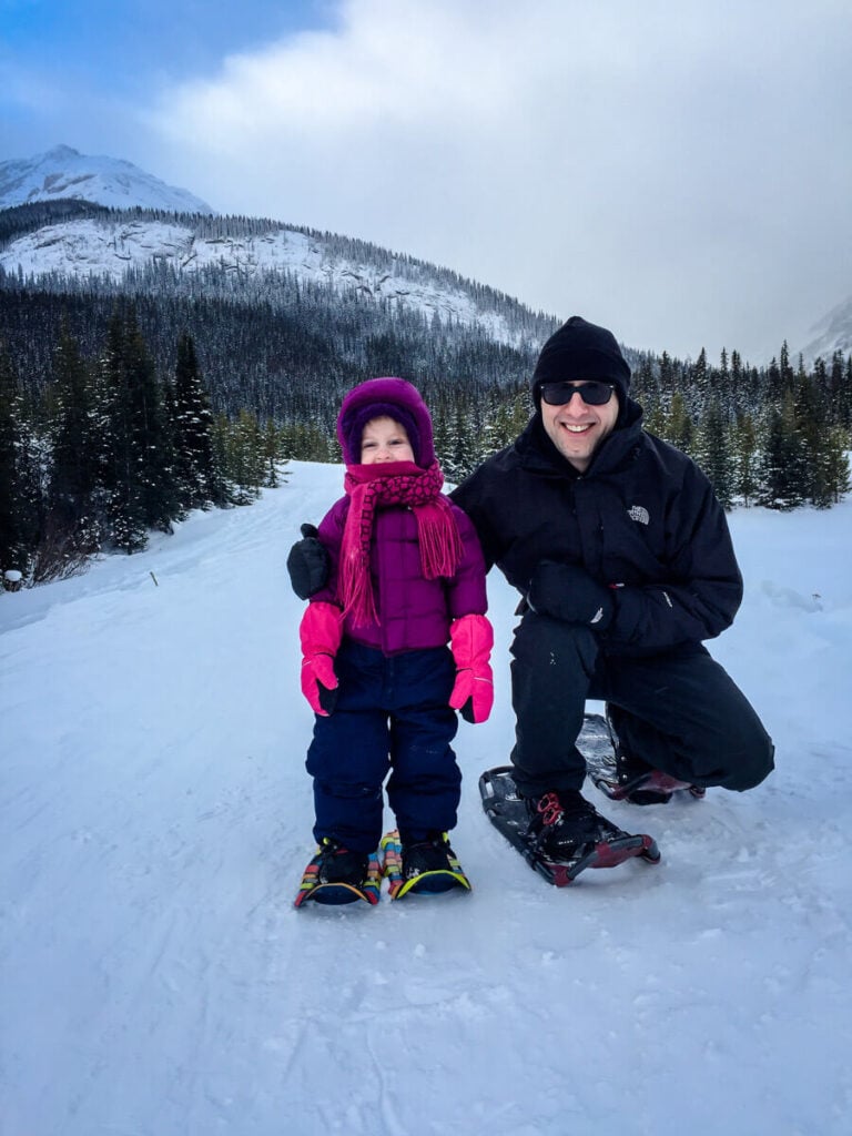 Father posing with daughter in snowshoes