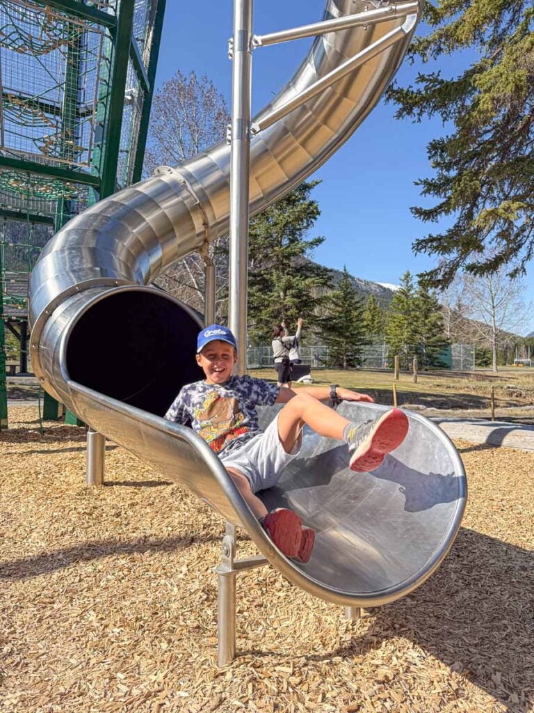 One of the Brewer kids, from BanffwithKids.com, plays on the large spiral slide at the Sundance Park in Banff.