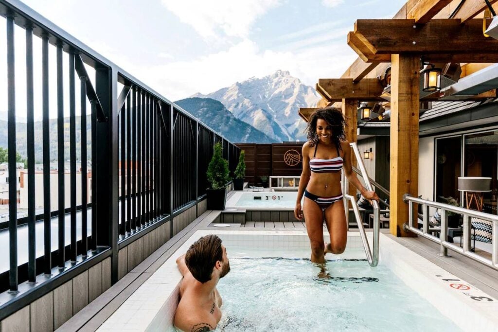 a young couple enjoys a soak in the rooftop hot tubs at the Mount Royal Hotel in central Banff.