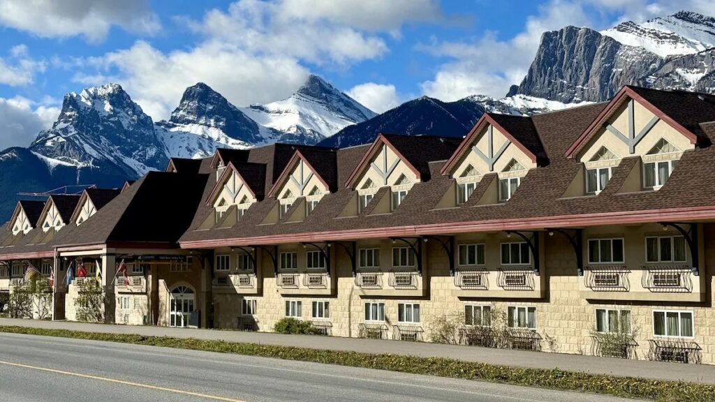 The exterior of the Canmore Inn & Suites in Canmore, Alberta with the Three Sisters Mountain behind.