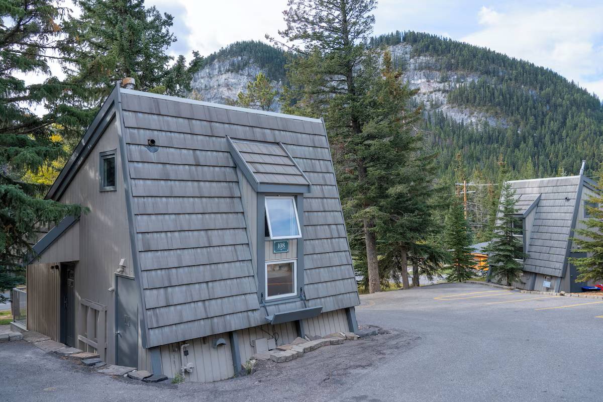 The exterior of the Mountain Cabin at Tunnel Mountain Resort in Banff with Tunnel Mountain in the background.