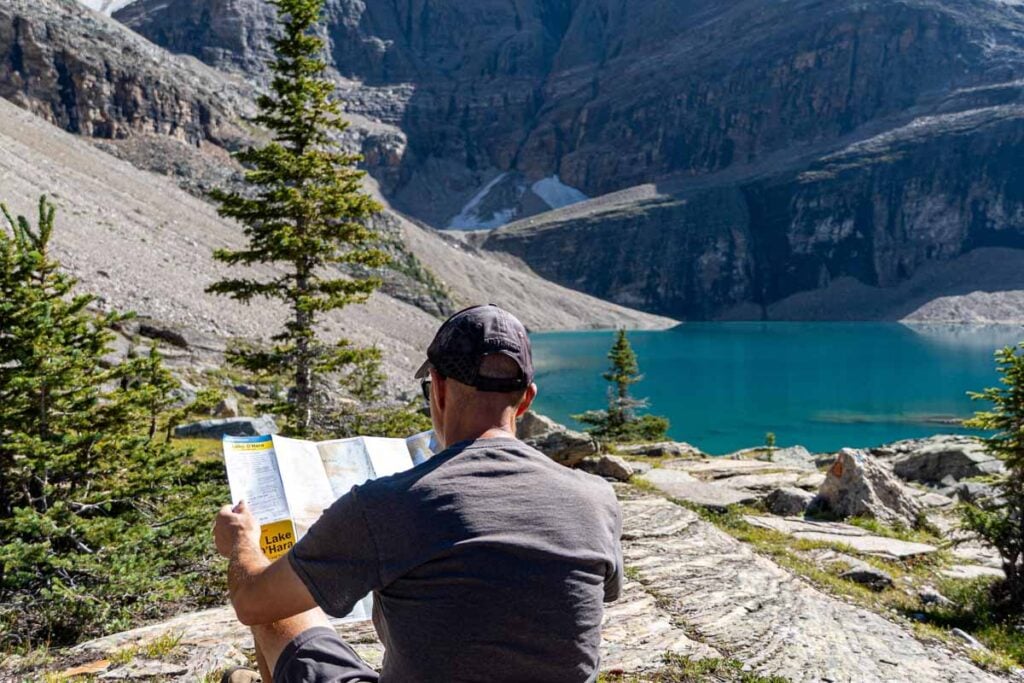 Dan Brewer, owner of TravelBanffCanada.com, reads his Lake O'Hara Gem Trek map while pausing at Lake Oesa.