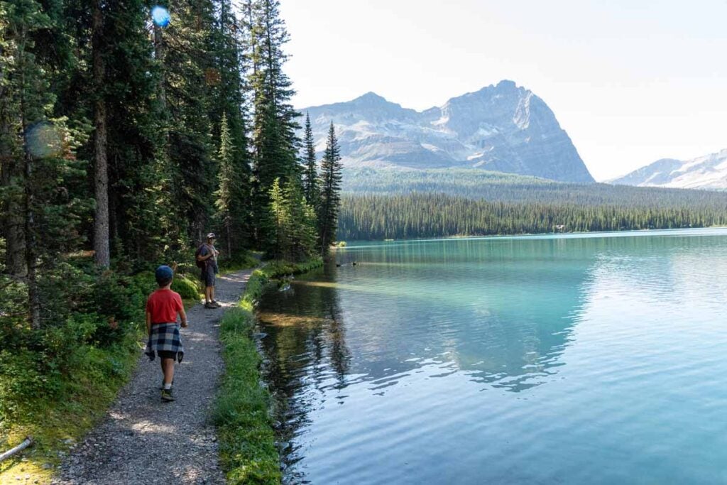 A family hikes along the tranquil shores of Lake O'Hara in Yoho National Park.