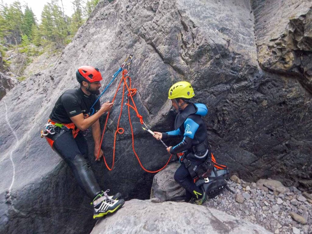 A guide helps a 9 year old boy safely rappel during a family-friendly canyoning tour in Banff.