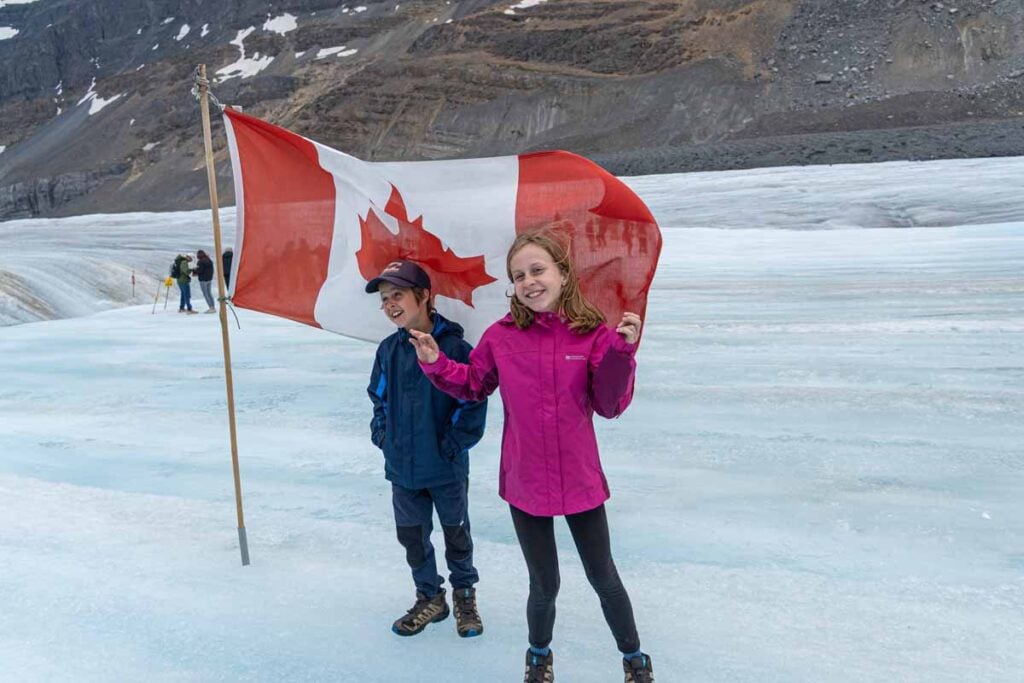 The Brewer kids pose for a picture with the Canada flag on the Athabasca Glacier.