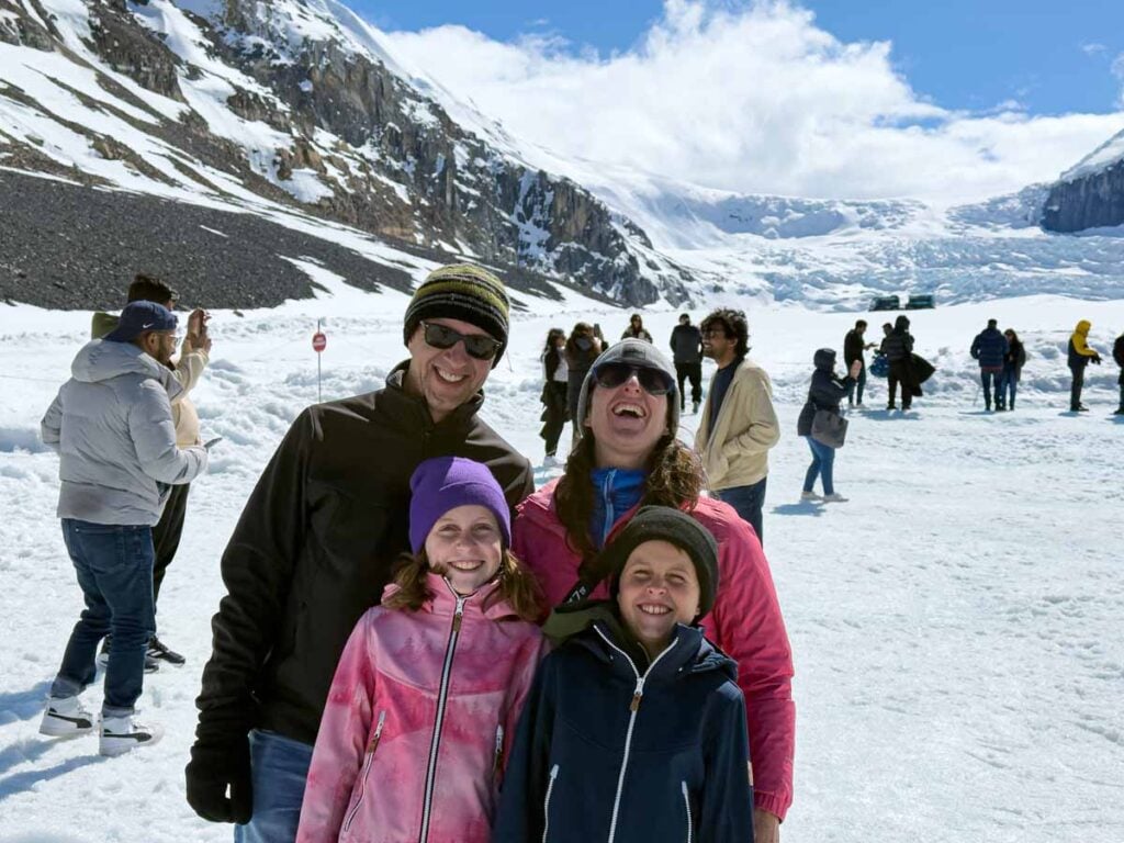 Dan and Celine Brewer, owners of TravelBanffCanada.com enjoy a laugh with their kids while standing on the Athabasca Glacier on a Columbia Icefield Adventure tour by Pursuit.
