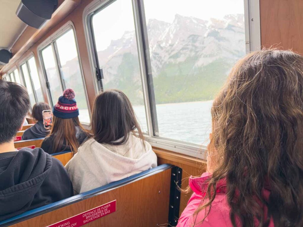 Celine Brewer, owner of the Travel Banff Canada blog, admires the mountain beauty through the window of the Lake Minnewanka Cruise boat.
