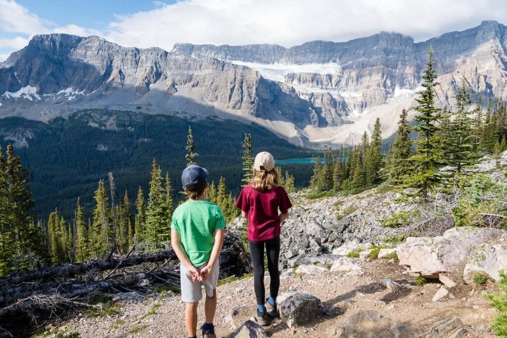 two kids look at Bow Lake and Crowfoot Glacier from Helen Lake hiking trail in Banff