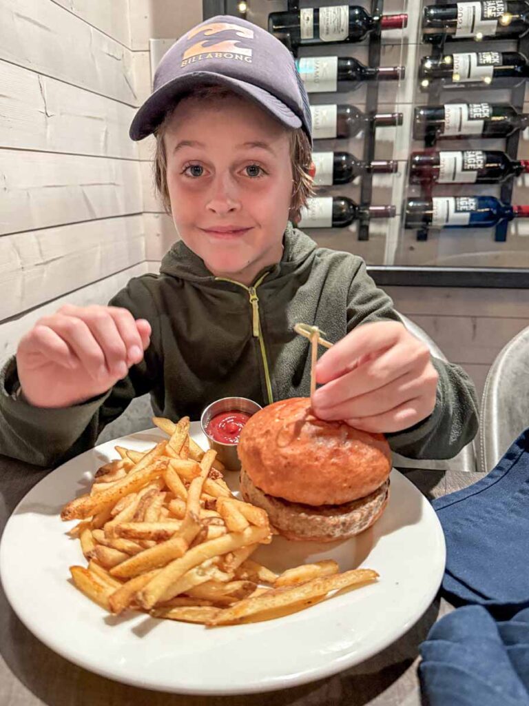 a 10-year old boy enjoys a hamburger at Evil Dave's Grill - located next door to the Marmot Lodge in Jasper, Canada.