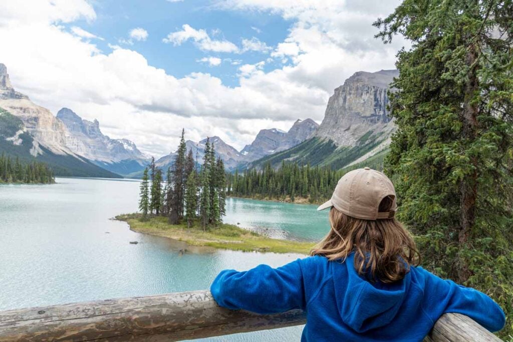 A 12 year old girl looks at Spirit Island with the Hall of the Gods in the background while on the Maligne Lake Boat Cruise in Jasper National Park.