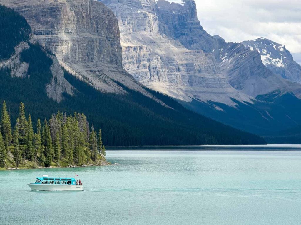 A Maligne Lake boat is dwarfed by the surrounding Rocky Mountains.