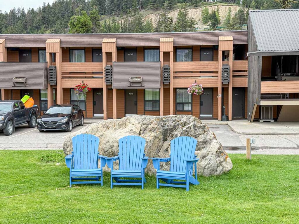 Three Adirondack chairs sit on the lawn of the Marmot Lodge in Jasper, Canada.