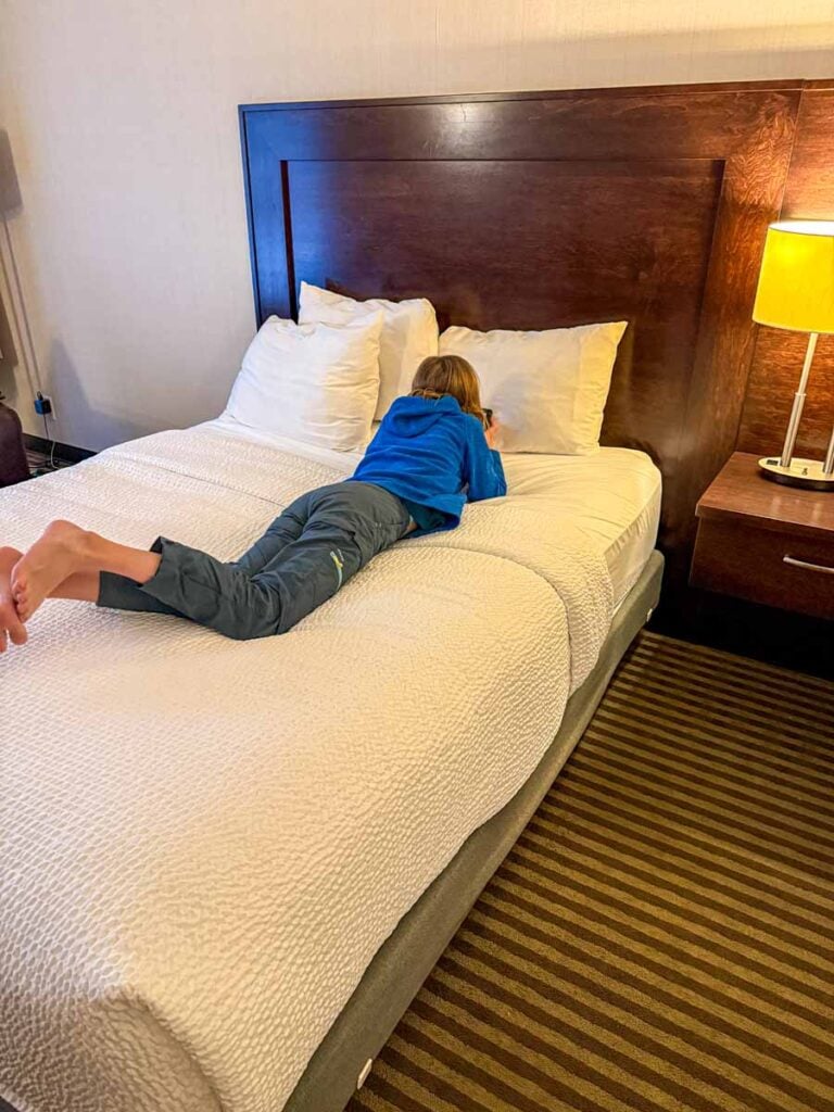 a 12-year old girl reads a book on the bed in her family's room at the Marmot Lodge in Jasper, Canada.