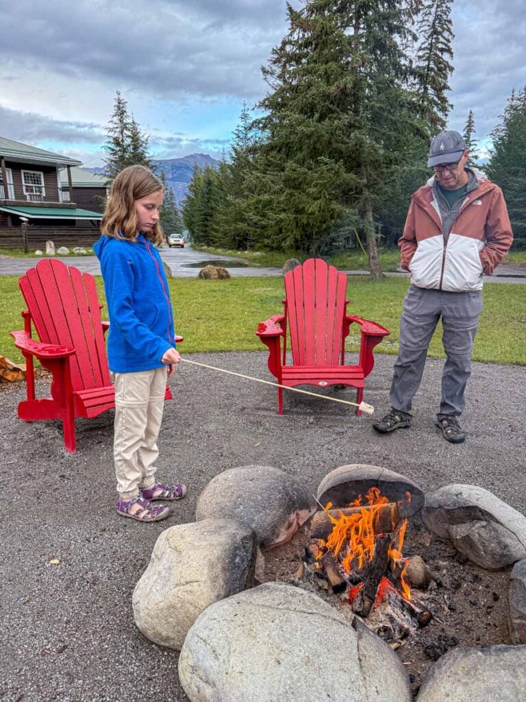 Dan Brewer, owner of TravelBanffCanada.com, watches his daughter roast a marshmallow over the campfire at the family-friendly Pine Bungalows in Jasper, Canada.
