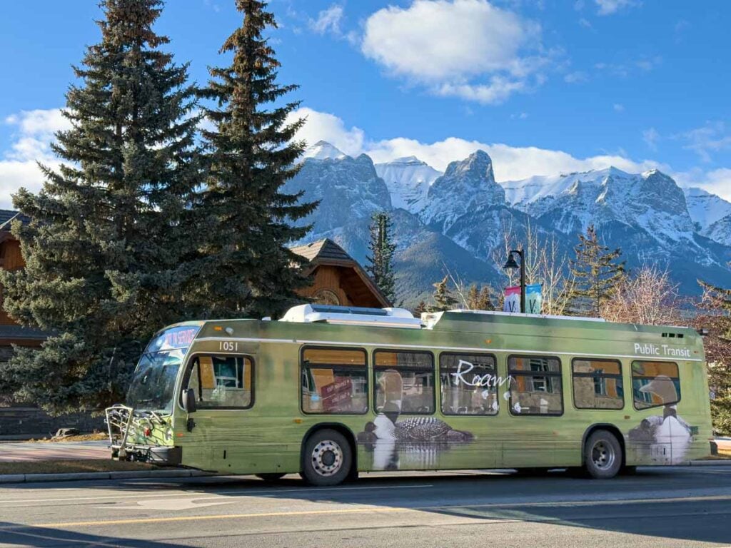 A Roam bus in Canmore, Alberta with a snow-capped Mt. Rundle in the background.