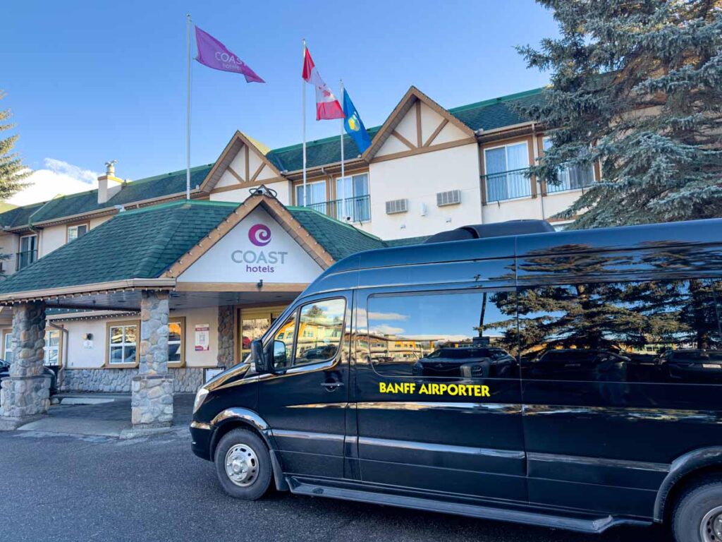 a small black Banff Airporter van is parked at the Canmore Coast Hotel.