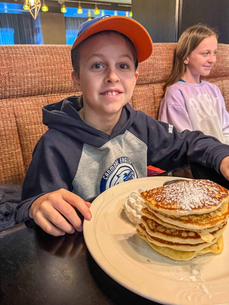 a 10-year old boy has a tall stack of pancakes at the Grande Kitchen + Bar - an excellent breakfast restaurant in Canmore.