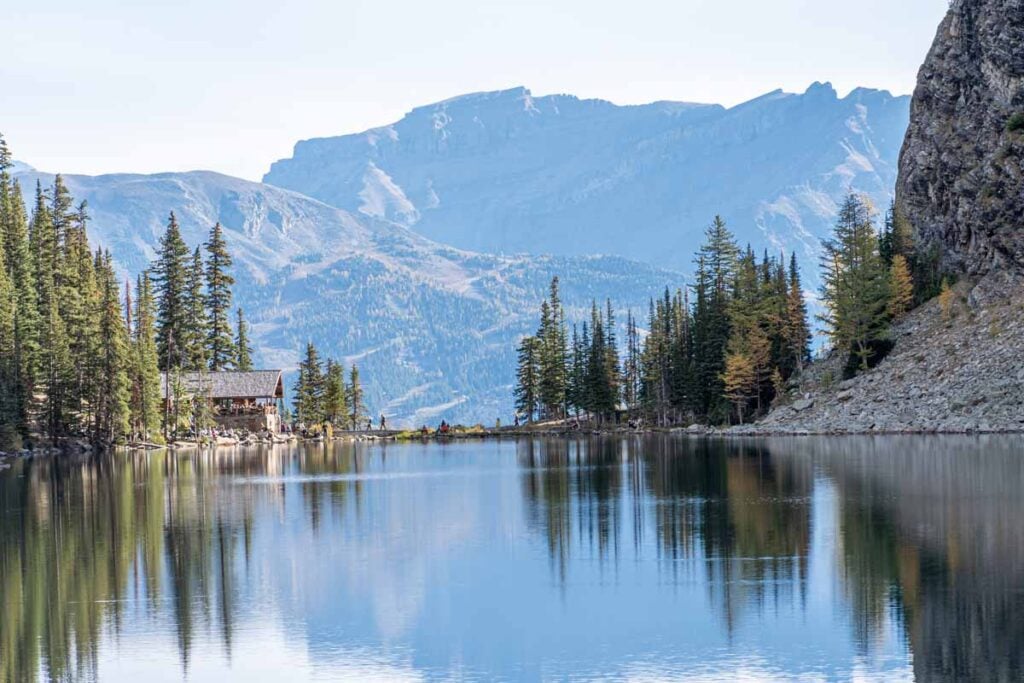 Looking across Lake Agnes with Lake Agnes Tea house in the distance and mountains behind it.