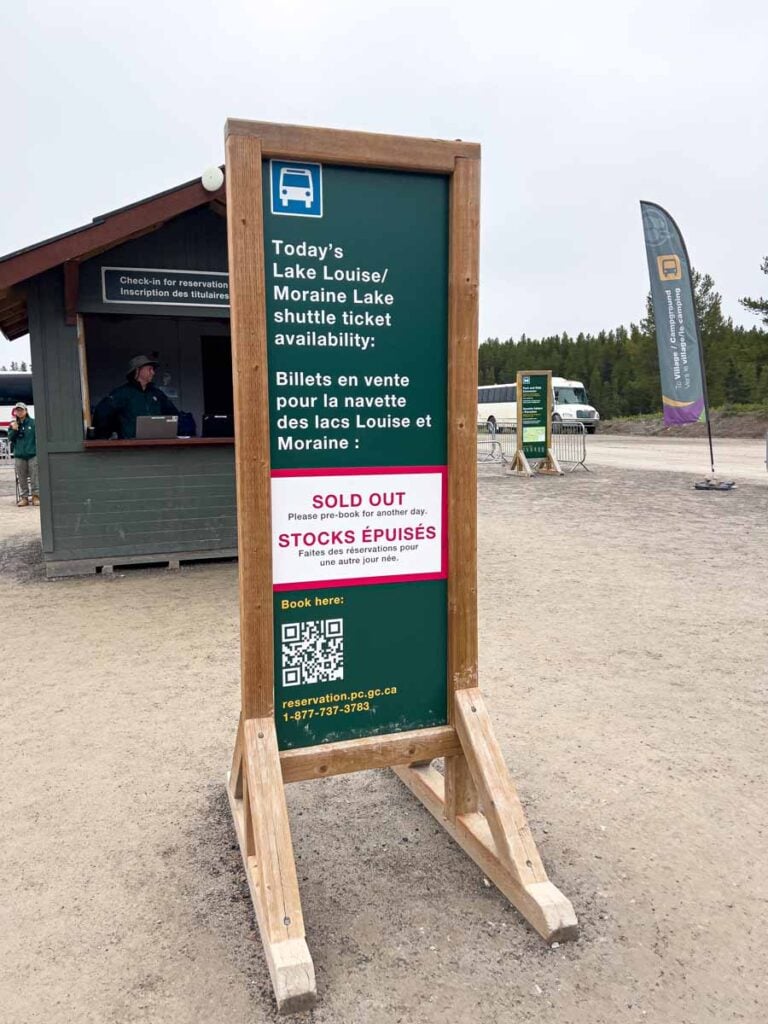 A Sold Out sign for the Lake Louise and Moraine Lake Shuttles at the Parks Canada shuttle booth in the Lake Louise parking lot.