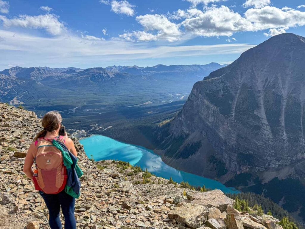 Celine Brewer, host of the Banff Travel Podcast, takes a picture of Lake Louise from the summit of Devil's Thumb.