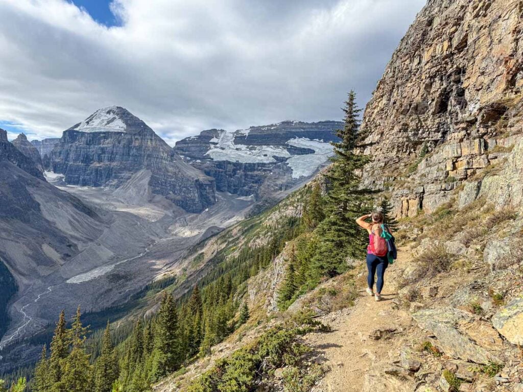 Celine Brewer, host of the Banff Travel Podcast, hikes the Devil's Thumb trail with glacier covered mountains ahead.