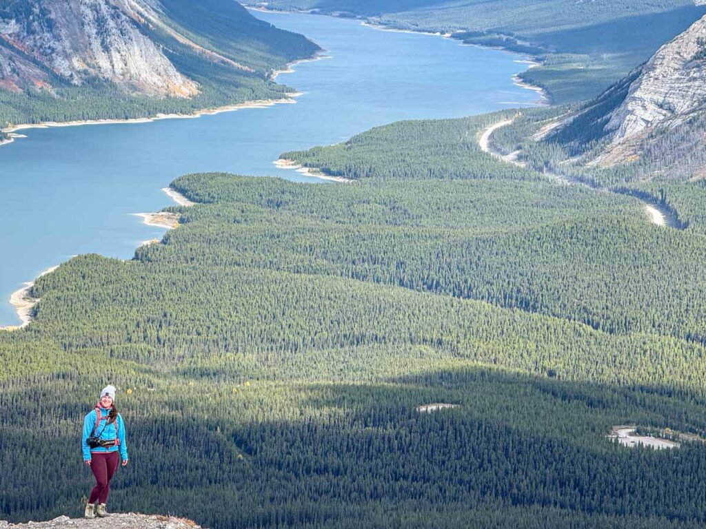 Celine Brewer, host of the Banff Travel Podcast, stands at the iconic viewpoint on the Tent Ridge Horseshoe Trail overlooking the Spray Lakes Reservoir.