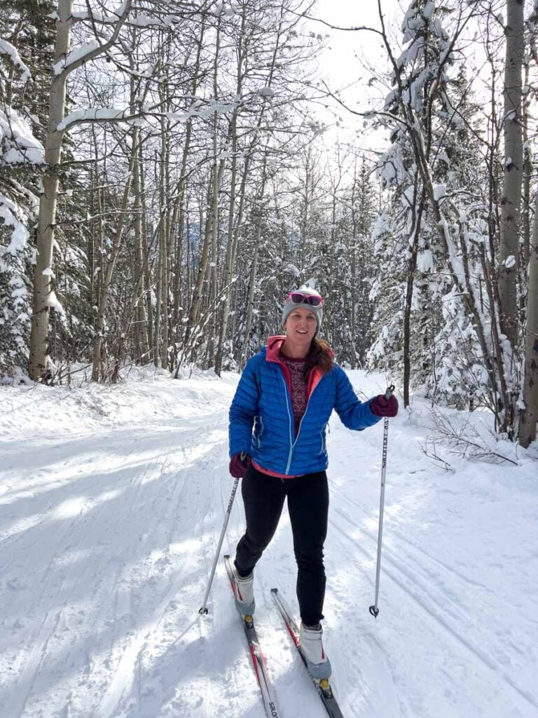 Celine Brewer, host of the Banff Travel Podcast, cross country skis on the Ribbon Creek Trail in Kananaskis.