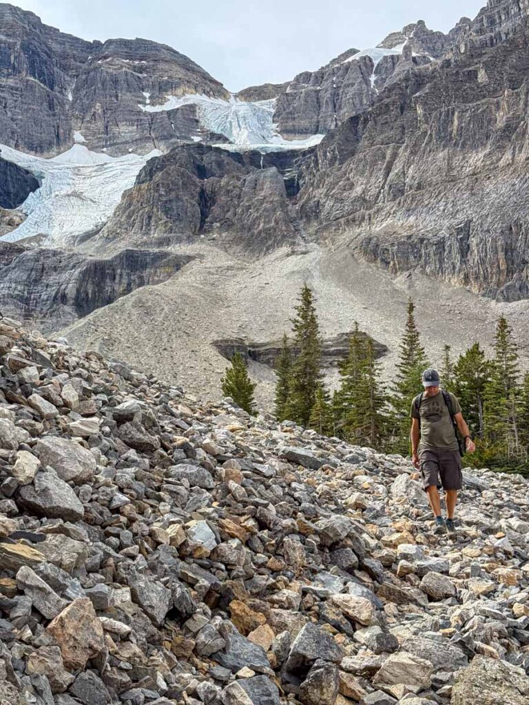 Dan Brewer, owner of the Travel Banff Canada blog, hikes downhill with the Stanley Glacier behind him.
