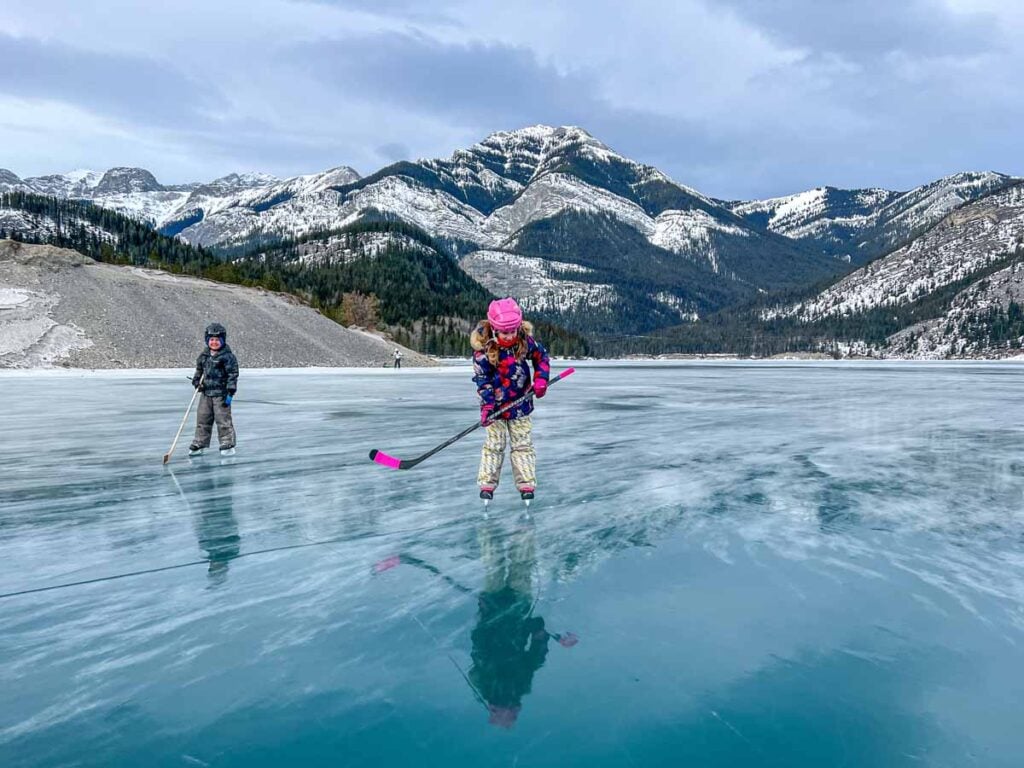 The Brewer kids, from TravelBanffCanada.com, play ice hockey while skating on Barrier Lake in Kananaskis Country.