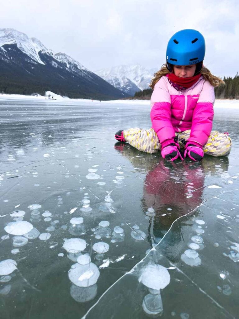 A Brewer child pauses to look at ice bubbles while skating at Spray Lakes in Kananaskis.