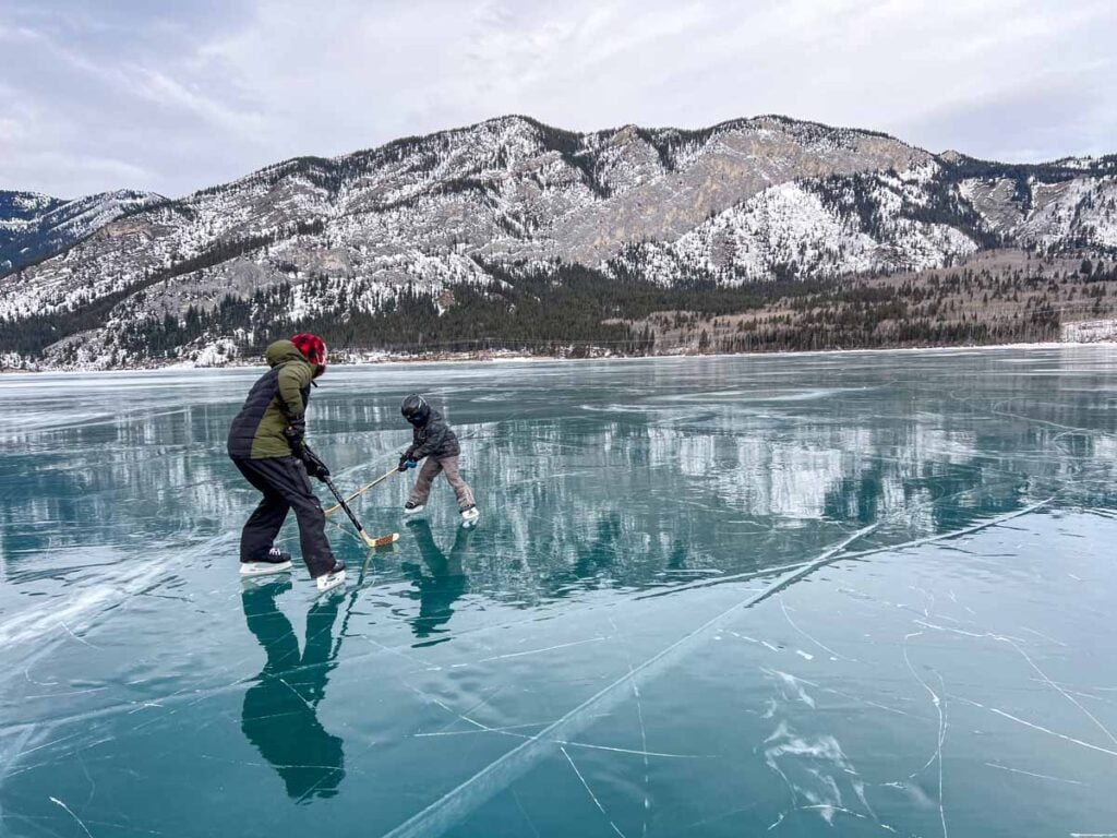 Dan Brewer, owner of TravelBanffCanada.com, plays ice hockey with his son on Barrier Lake in Kananaskis Country.