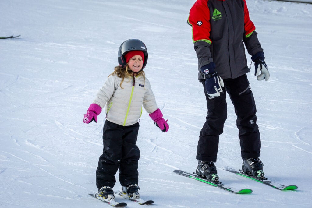 A young Brewer girl on skis beside her instructor during a beginner ski lesson at Mt. Norquay in Banff.
